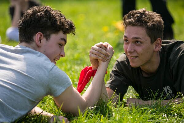 Zwei Jungen liegen auf einer Wiese und machen Armdrücken.