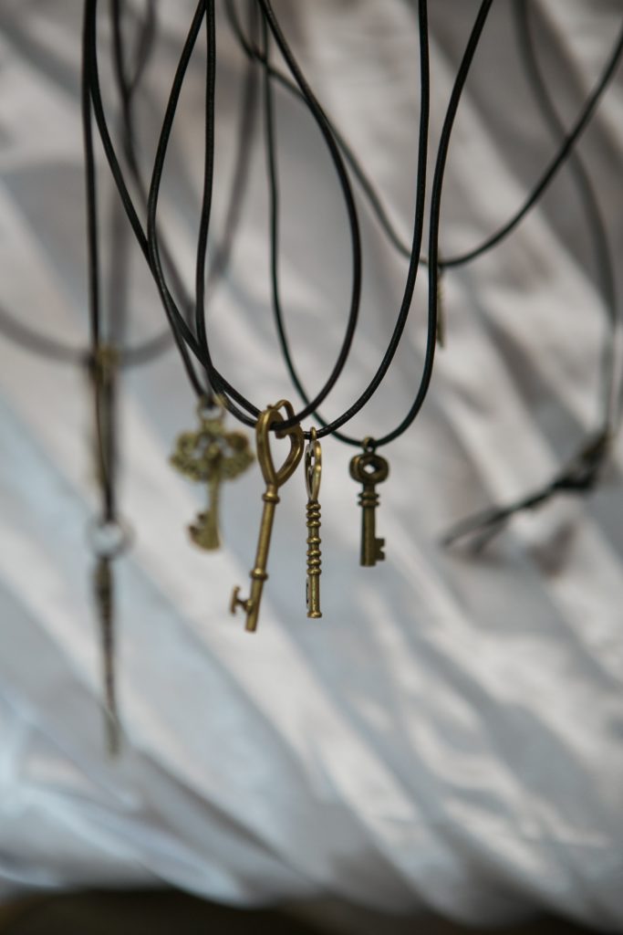 Sechs goldene Schlüssel hängen an schwarzen Bändern.