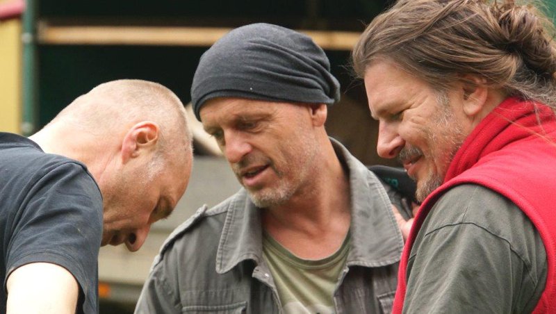 Drei Männer stehen zusammen, beraten sich und lächeln.